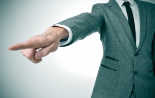 a man wearing a suit pointing with the finger the way out